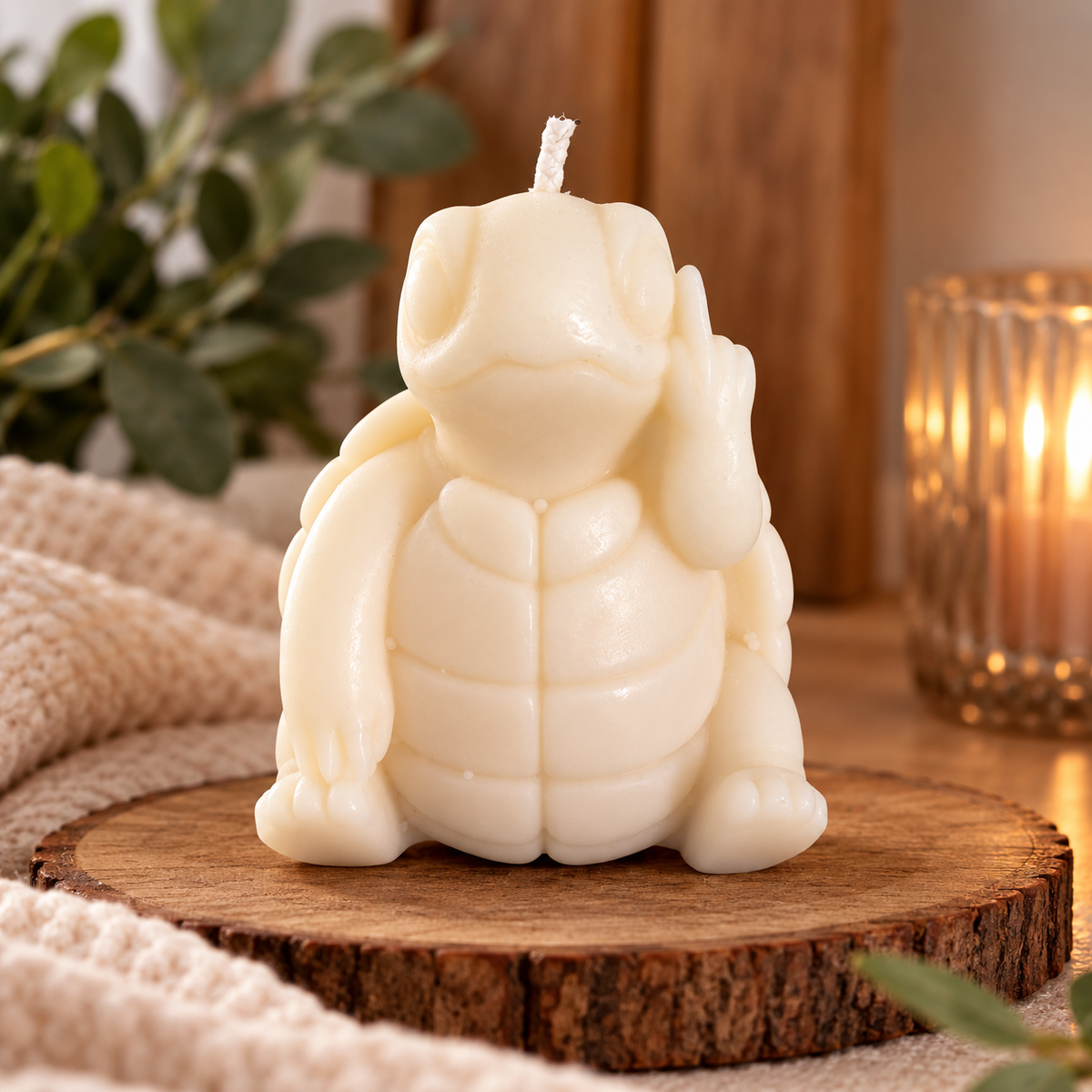 Ivory turtle-shaped candle with sculpted shell and one hand raised, on a wooden display